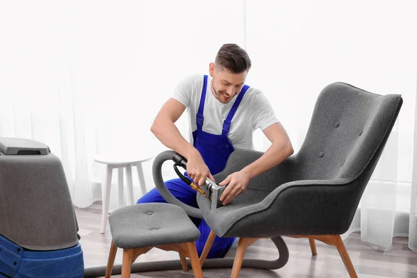 Dry cleaning worker removing dirt from armchair indoors