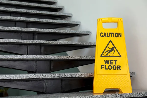 Safety sign with phrase Caution wet floor on stairs. Cleaning service