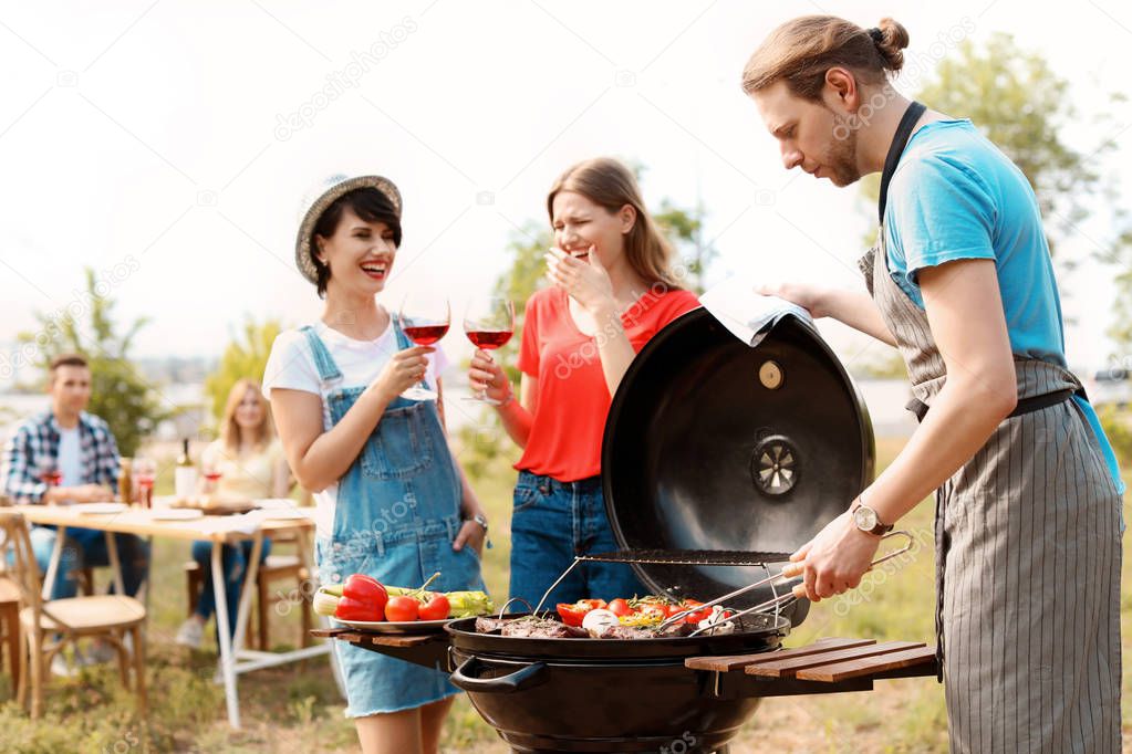 Young people having barbecue with modern grill outdoors