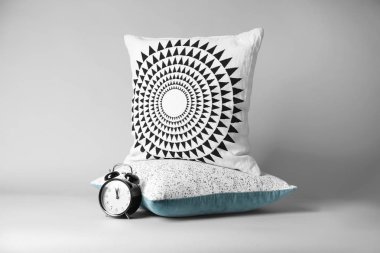 Yumuşak dekoratif yastıklar ve açık renkli çalar saat