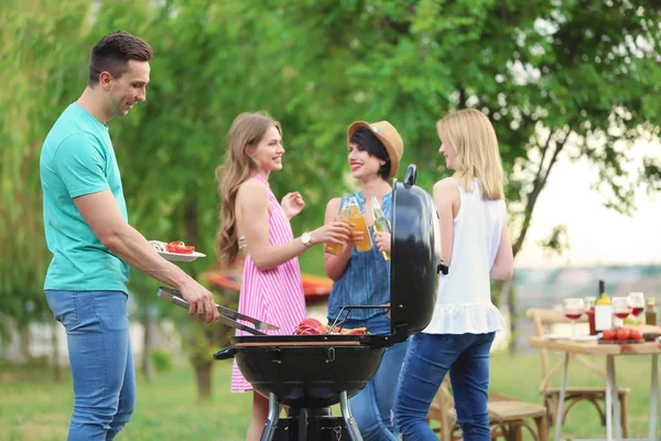 Young people having barbecue with modern grill outdoors