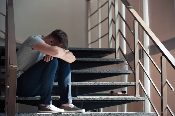 Merdivenlerde oturan depresif genç adam