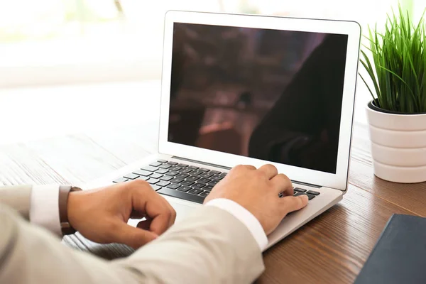 Man in office wear using laptop at table indoors