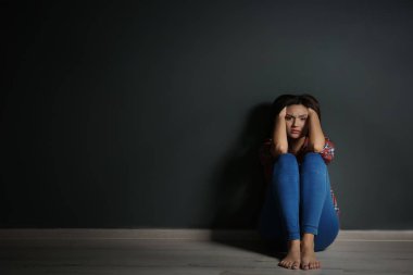 Katta karanlıkta oturan depresif genç kadın