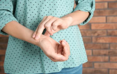 Genç kadın darbe tuğla duvar arka plan üzerinde kontrol