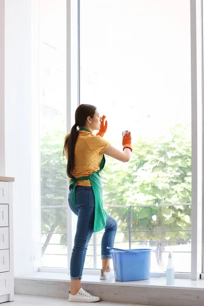 年轻妇女清洁窗口玻璃在家里 — 图库照片