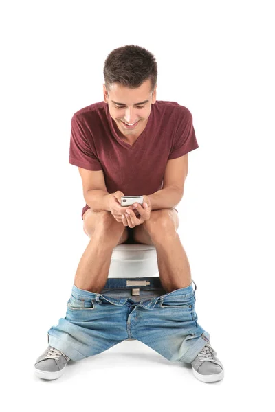 Jovem Usando Telefone Celular Enquanto Sentado Vaso Sanitário Isolado Branco — Fotografia de Stock