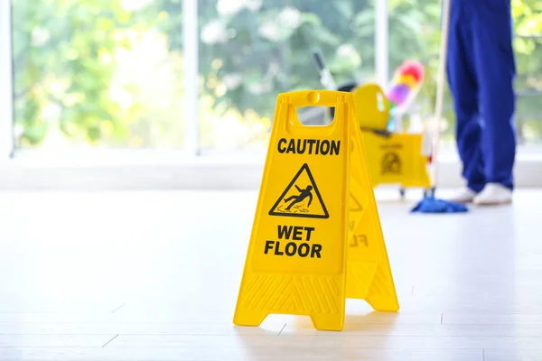 Safety sign with phrase Caution wet floor and cleaner indoors. Cleaning service