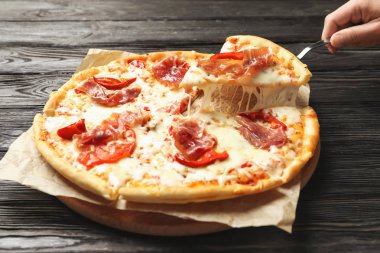 Kürek ile lezzetli sıcak pizza dilim masa üzerinde closeup tutan kadın