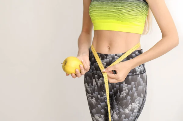新鮮なリンゴと明るい背景に測定テープを持つ女性 健康的な食事 — ストック写真