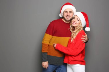 Noel Baba şapkaları gri arka plan üzerinde genç çift. Noel kutlamaları