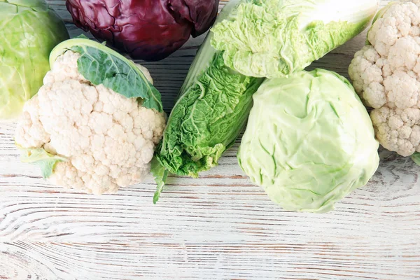 Ahşap arka plan üzerinde farklı lahana ile düz yatıyordu kompozisyon