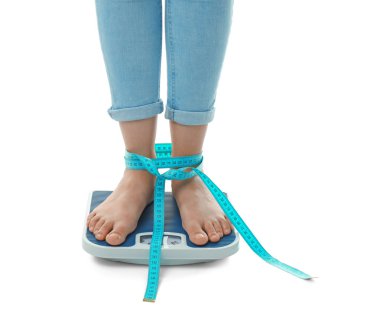 Kadın onun ağırlık kullanarak ölçüm bandı ile beyaz arka plan üzerinde ölçekler. Sağlıklı beslenme