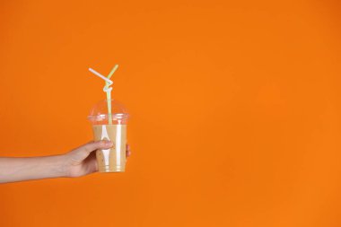 Renk arka plan üzerinde sağlıklı güler yüzlü plastik bardak tutan genç kadın
