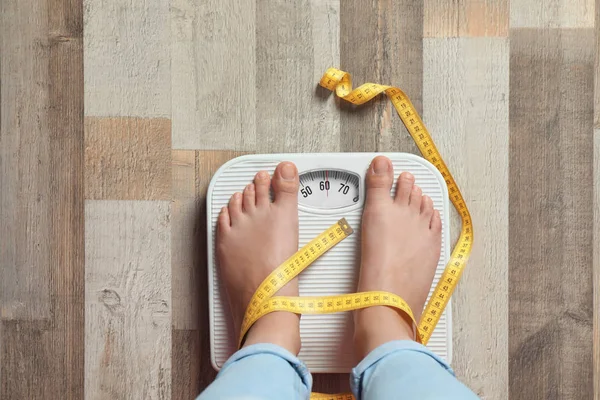有腿的女人用地板上的鳞片来测量她的体重 健康饮食 — 图库照片