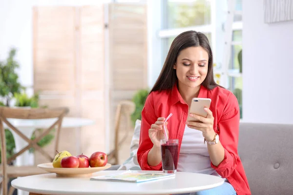 Jovem Mulher Usando Telefone Celular Enquanto Bebe Saboroso Smoothie Saudável — Fotografia de Stock