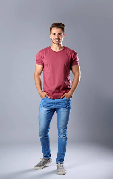 Young man in stylish jeans on grey background