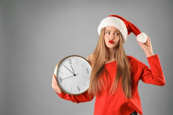 Jovem Mulher Bonita Chapéu Santa Segurando Grande Relógio Fundo Cinza — Fotografia de Stock