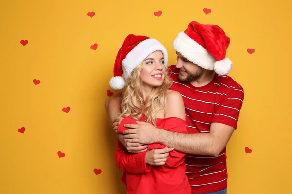Genç Çift Renk Arka Plan Üzerinde Santa Şapkalar Noel Kutlamaları — Stok fotoğraf