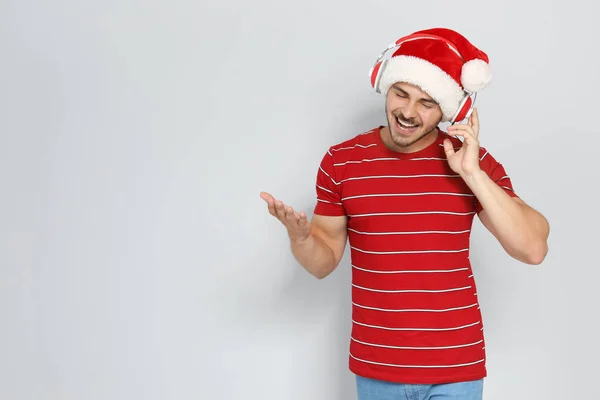 Junger Mann Mit Weihnachtsmütze Hört Weihnachtsmusik Auf Farbigem Hintergrund — Stockfoto