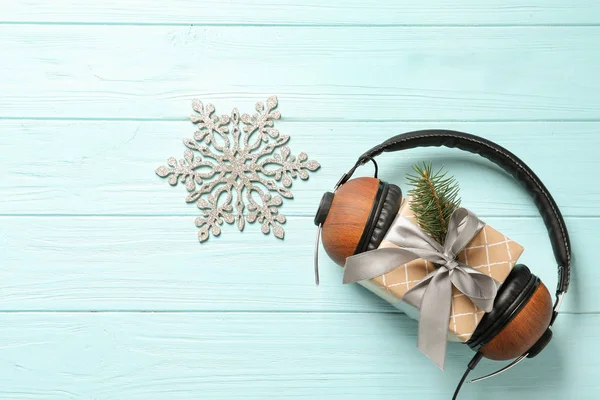Flat lay composition with gift box and headphones on wooden background. Christmas music concept