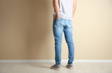 Genç adam ışık duvarının yakınında şık kot pantolon