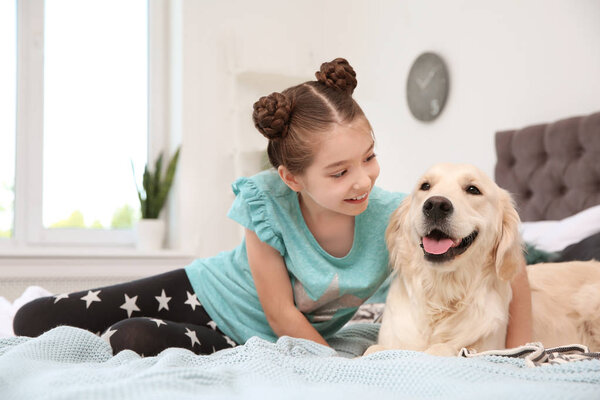 Cute little child with her pet on bed at home