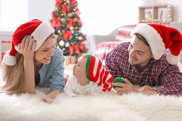 クリスマスの帽子を自宅で赤ちゃんと幸せなカップル — ストック写真