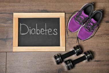 Word diyabet, spor ayakkabı ve ahşap arka plan üzerinde halter ile düz yatıyordu kompozisyon