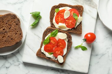 Tost ekmeğine kiraz domates ve mozzarella peyniri mermer kurulu, üstten görünüm