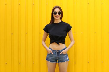 Sokakta renk duvarının yakınında siyah t-shirt giyen genç kadın