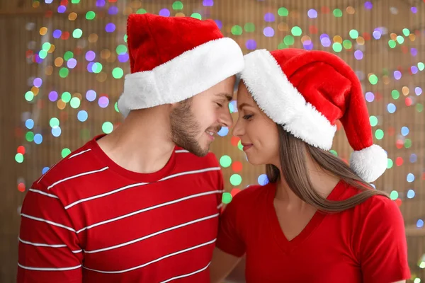 Pareja Joven Sombreros Santa Sobre Fondo Borroso Luces Celebración Navidad —  Fotos de Stock