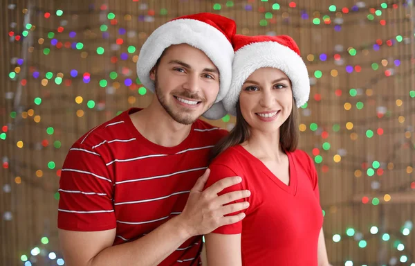Noel Baba Şapkaları Bulanık Işıklar Arka Plan Üzerinde Genç Çift — Stok fotoğraf