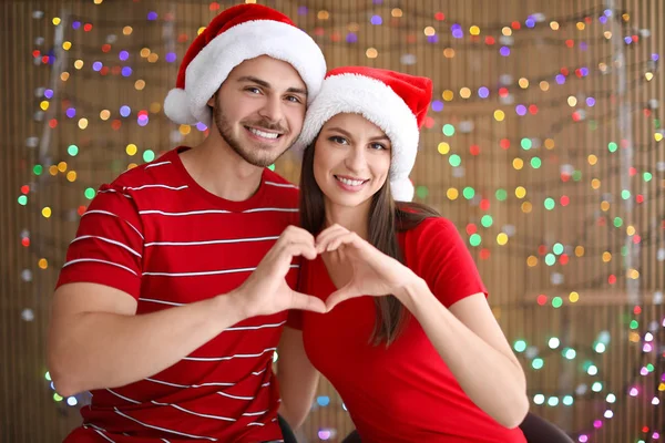 Kalp Şeklinde Bulanık Ellere Santa Şapkalar Içinde Genç Çift Arka — Stok fotoğraf