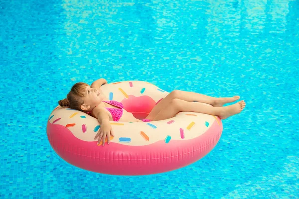 Happy girl relaxing on inflatable ring in swimming pool