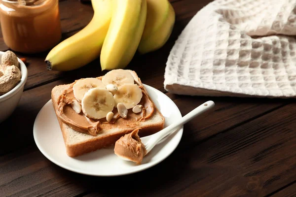 Toast bread with peanut butter and banana slices on wooden table