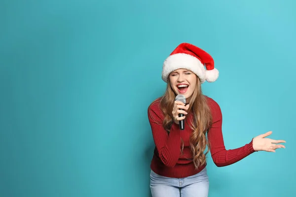 Młoda Kobieta Santa Hat Śpiewa Mikrofonu Kolor Tła Muzyka Świąteczna — Zdjęcie stockowe
