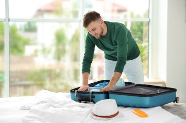 Genç adam bavul yatak yaz yolculuk için paketleme