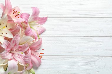 Ahşap arka plan üzerinde güzel çiçek açan lily çiçekler ile düz yatıyordu kompozisyon