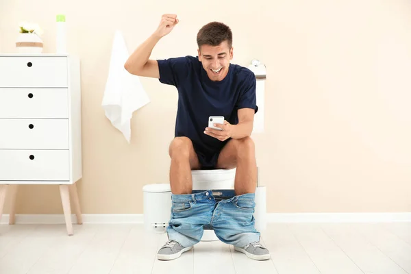 Jovem Usando Telefone Celular Enquanto Sentado Bacia Banheiro Casa — Fotografia de Stock