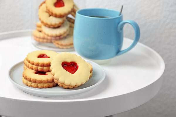 Traditional Christmas Linzer cookies with sweet jam and cup of tea on table