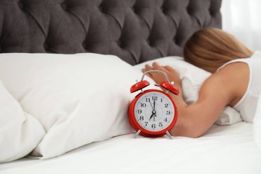 Analog alarm saat ve uykulu kadın yatakta. Günün saati