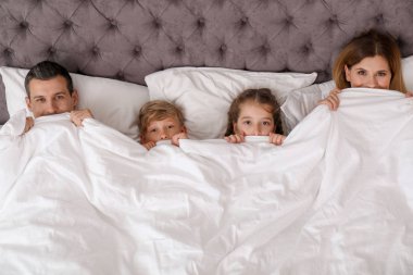 Yatakta battaniyenin altında yalan çocuklu bir çift gördüm. Mutlu bir aile