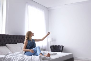 Genç kadın ile uzaktan kumanda evde Klima işletim