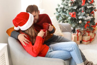 Mutlu genç birkaç bardak sıcak kutluyor Noel evde içecek