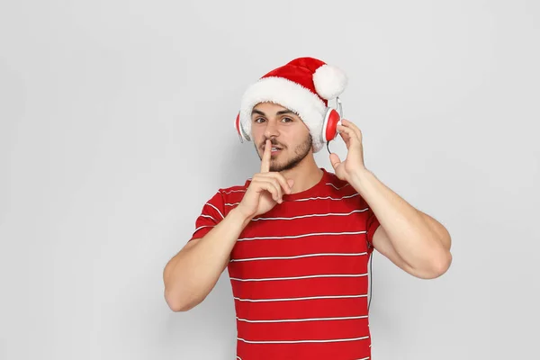 Junger Mann Mit Weihnachtsmütze Hört Weihnachtsmusik Auf Farbigem Hintergrund — Stockfoto