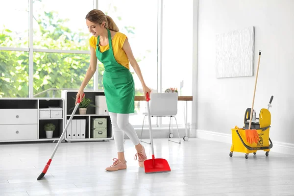 Νεαρή Γυναίκα Σκούπα Και Dustpan Καθαρισμού Στο Γραφείο — Φωτογραφία Αρχείου