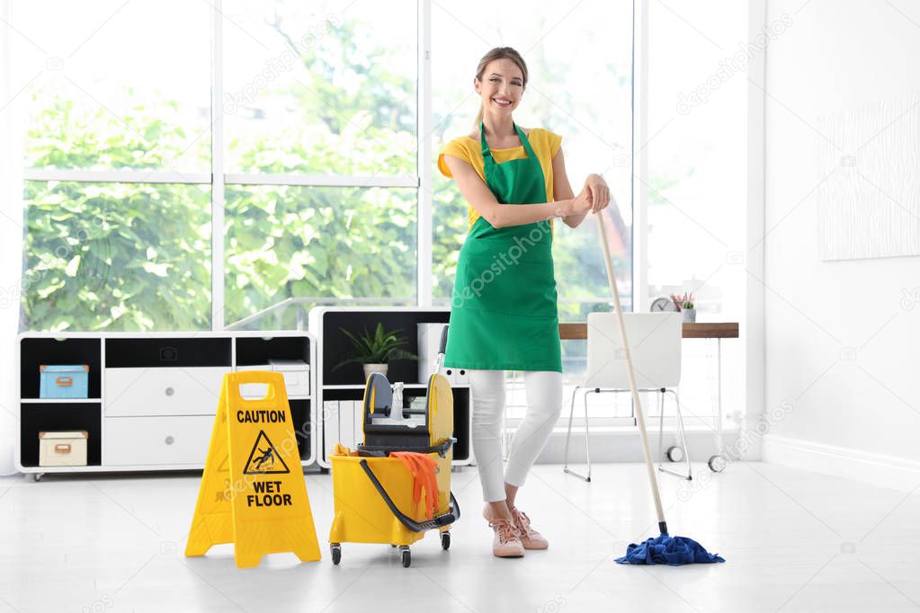 Young woman with mop and bucket cleaning office