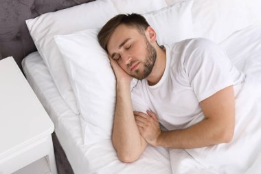 Evde yatakta uyuyan yakışıklı delikanlı. Sabah erken