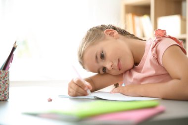 Sevimli küçük çocuk sınıfta masasında atama yapıyor. İlköğretim Okulu